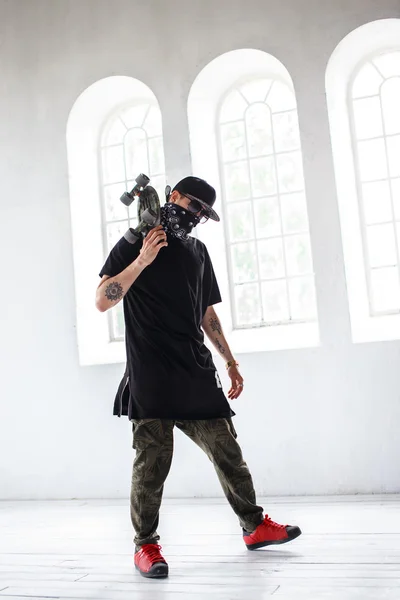 Homem em uma máscara mantém skate — Fotografia de Stock