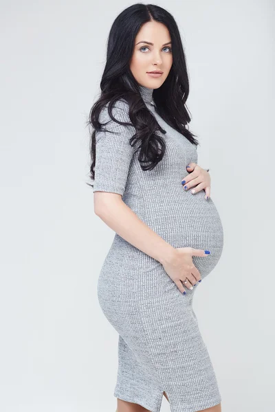 Těhotná bruneta žena v šedých šatech — Stock fotografie