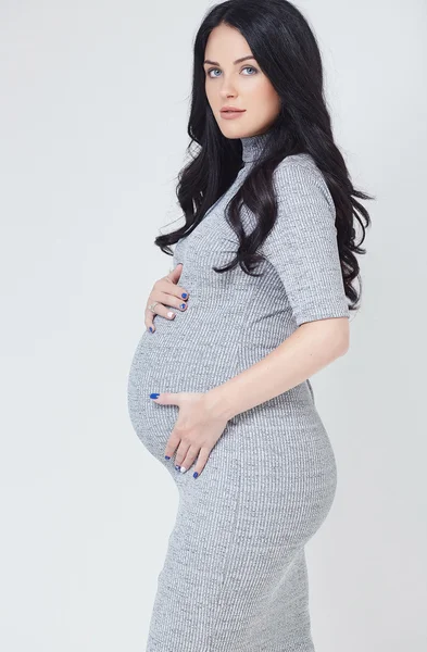 Donna bruna incinta in un vestito grigio — Foto Stock