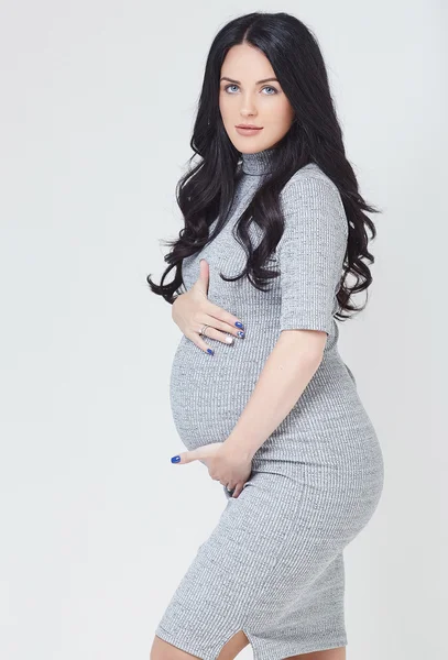 Zwangere brunette vrouw in een grijze jurk — Stockfoto