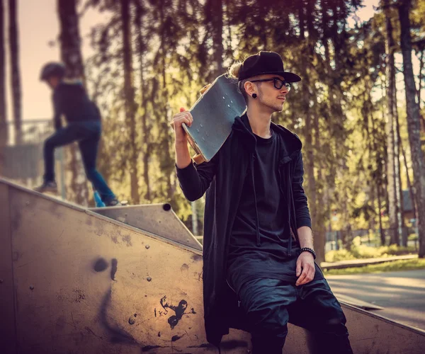 Mens in zwarte kleren poseren met skateboard — Stockfoto