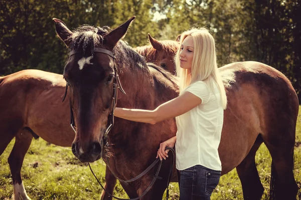 Mujer rubia posando con caballos marrones — Foto de Stock