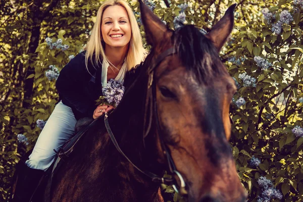 Mujer rubia sentada a caballo . — Foto de Stock