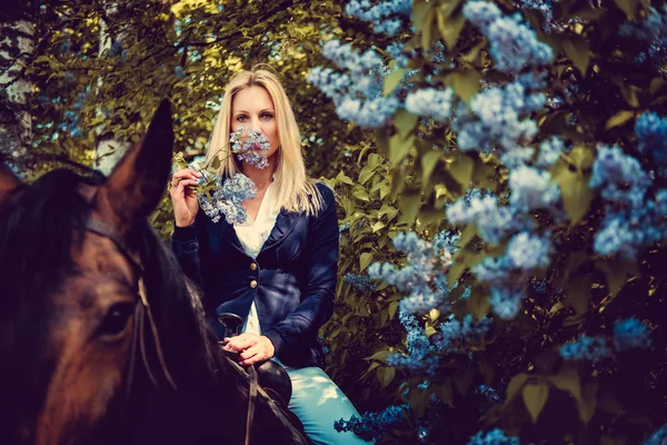 At sırtına oturan sarışın kadın.