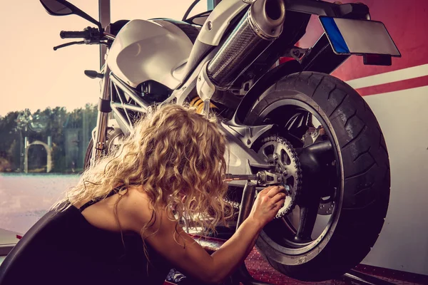 Sexy blonde Frau repariert Motorrad. — Stockfoto