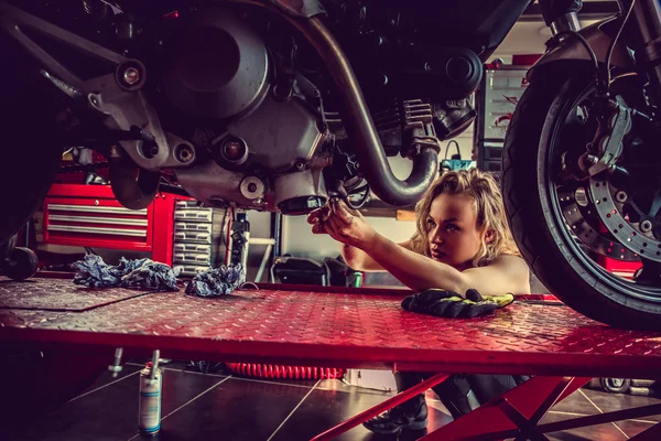 Blond kvinna reparera motorcykel. — Stockfoto