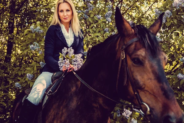 At sırtına oturan sarışın kadın.