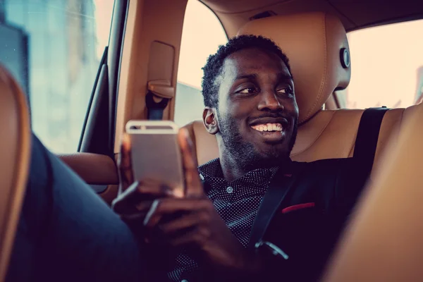 Hombre negro sonriente usando teléfono inteligente — Foto de Stock