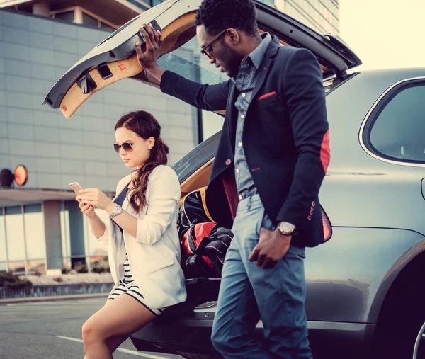 Internationella par med smartphone nära bil. — Stockfoto
