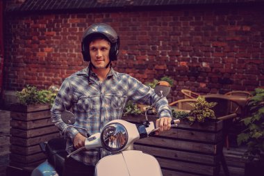 Bir adam eski şehirde beyaz moto scooter üzerinde.