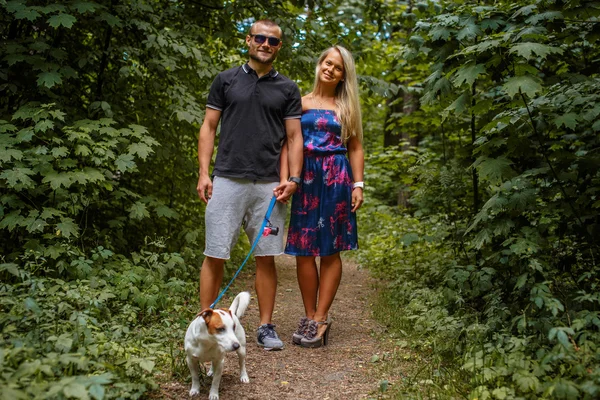 Atractiva pareja en un paseo con un perro — Foto de Stock