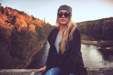 Bir köprü üzerinde oturan sarışın kadın