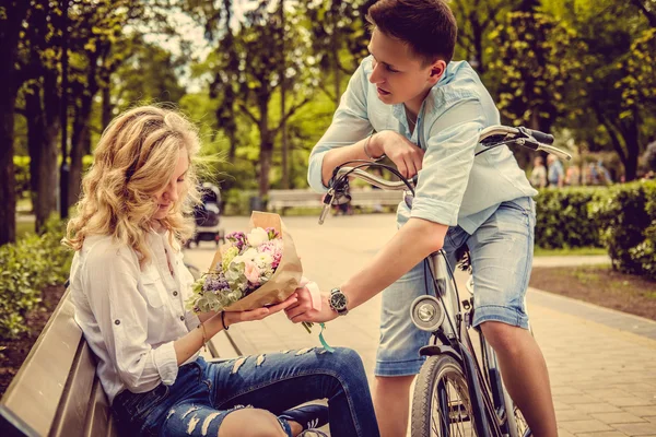 Man op een fiets geeft bloemen aan zijn vriendin — Stockfoto