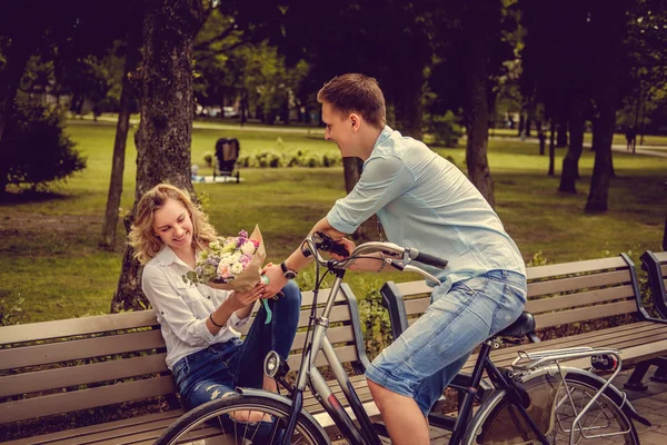 Man på en cykel ger blommor till sin flickvän — Stockfoto