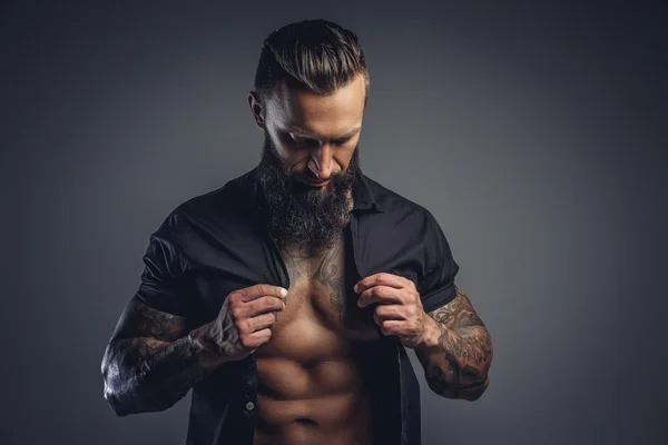Tattooed male taking off his shirt — Stock Photo, Image