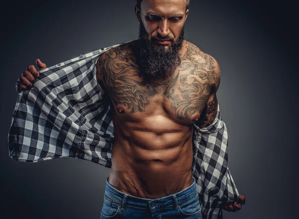 Tattooed male taking off his shirt — Stock Photo, Image