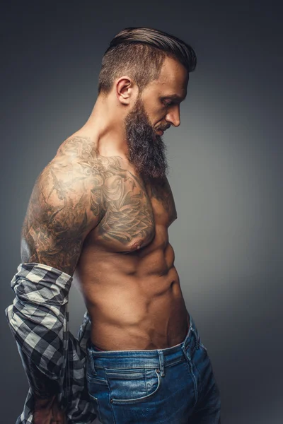 Hombre tatuado quitándose la camisa — Foto de Stock
