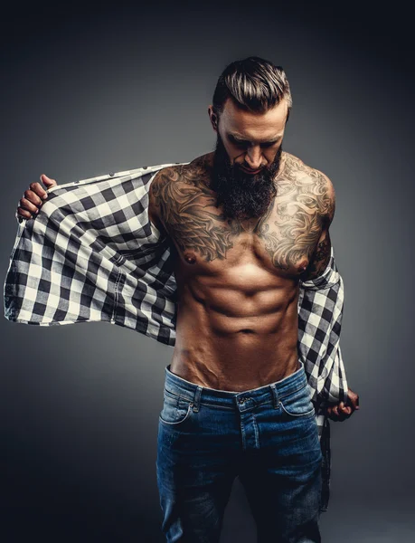 Татуированный мужчина снимает рубашку — стоковое фото