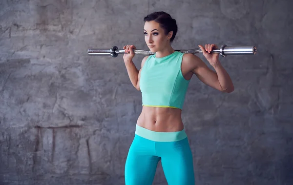 Feminino em azul sportswear segurando barbell — Fotografia de Stock