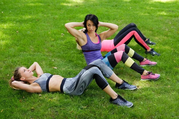 Tres chicas deportivas haciendo ejercicios abdominales —  Fotos de Stock