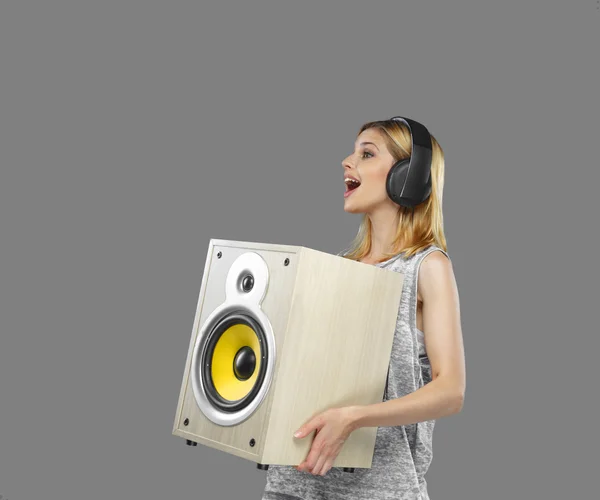 Blond female in earphones holding subwoofer — Stock Photo, Image