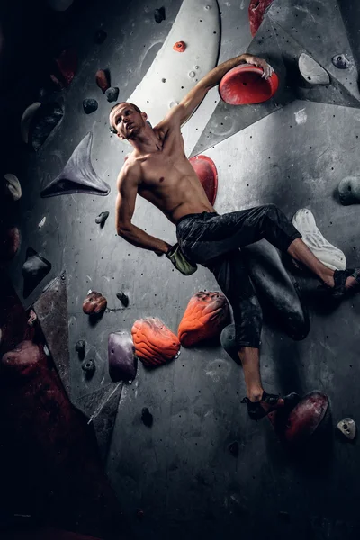 Hombre escalando en un muro de escalada interior — Foto de Stock