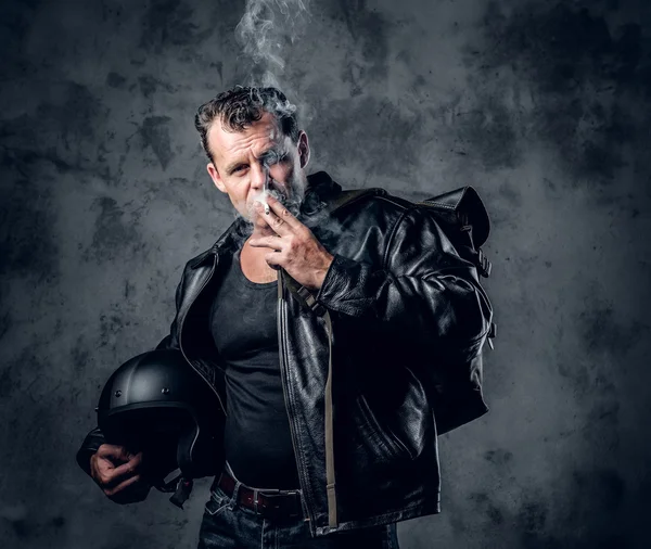 Um homem de casaco de couro fumando um cigarro — Fotografia de Stock