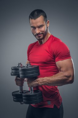 Erkek bir kırmızı t shirt dumbbells tutar