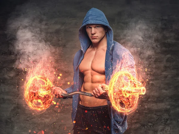 Male in a hoodie holds the burning barbell — Stock Photo, Image