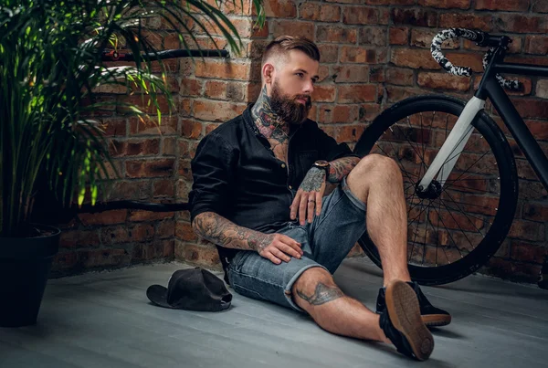 Maschio hipster tatuato si siede su un pavimento — Foto Stock