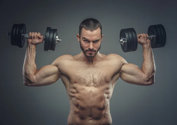 Mann hält Hanteln mit erhobenen Armen — Stockfoto