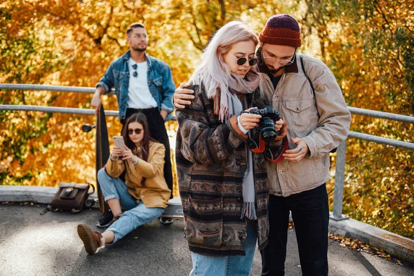 Компания друзей, отдыхающих и фотографирующих в осеннем парке — стоковое фото