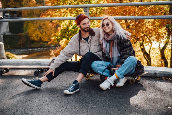 Embracing couple in love sitting on skate on the bridge — Stock Photo, Image