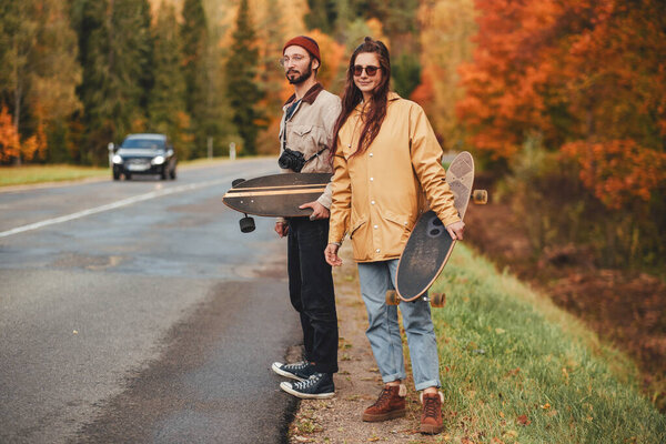Couple of girl and guy hitchhiking in autumn forest