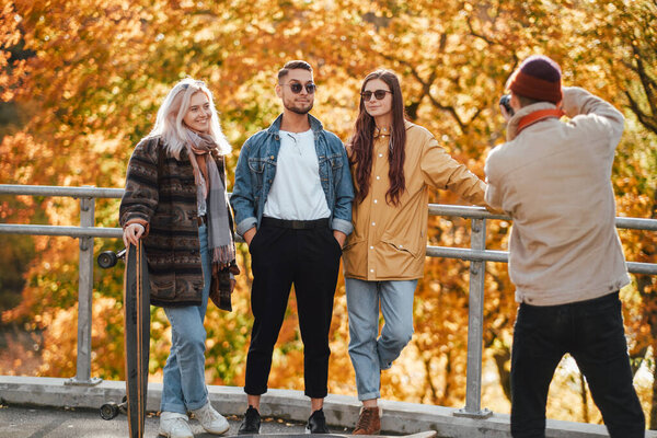 Joyful four friends photographing in auturm park