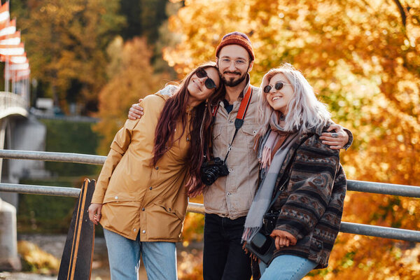 Group of three friends posing in autumn park