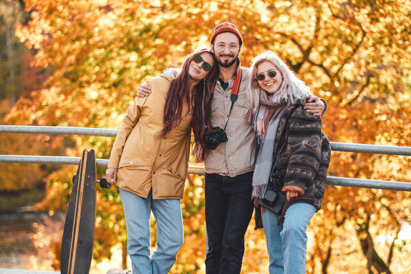 Group of three friends posing in autumn park
