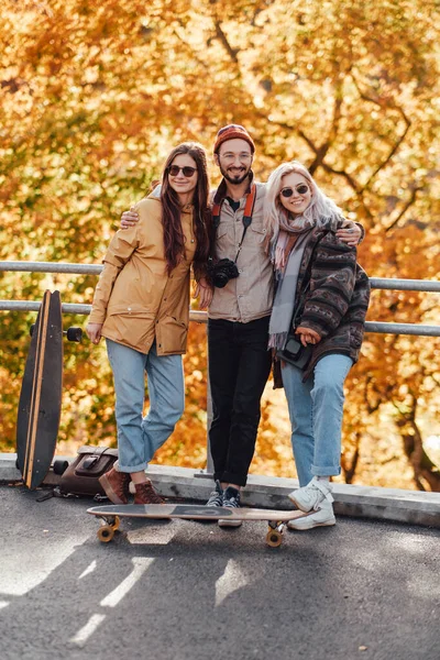 Chico y dos chicas bonitas posando en el puente en el parque de otoño — Foto de Stock