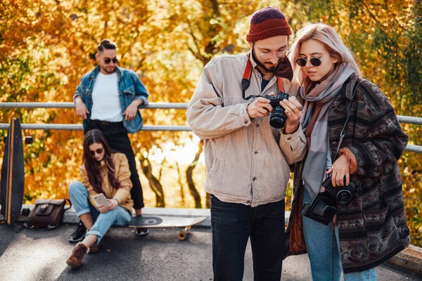 Компания друзей, отдыхающих и фотографирующих в осеннем парке — стоковое фото