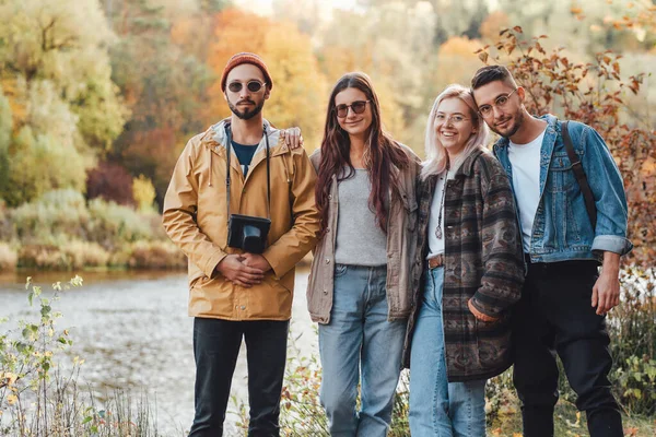 Bedrijf van vier vrienden wandelen in de herfst bos — Stockfoto