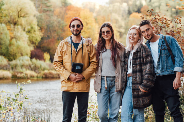 Company of four friends walking in autumn forest