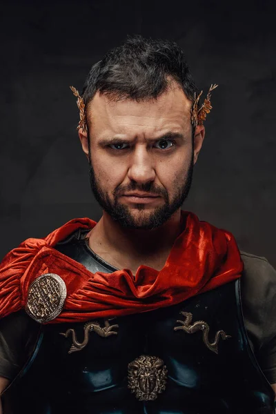 Serio imperatore romano vestito con armatura scura e mantello rosso — Foto Stock
