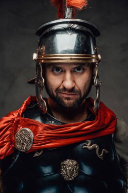 Karanlık arka planda kameraya bakan neşeli Romalı savaşçı.