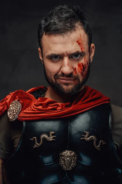 Serious roman emperor dressed in dark armour and red cloak — Stock Photo, Image
