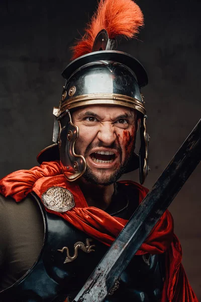 Бешеный римский солдат с мечом на темном фоне — стоковое фото