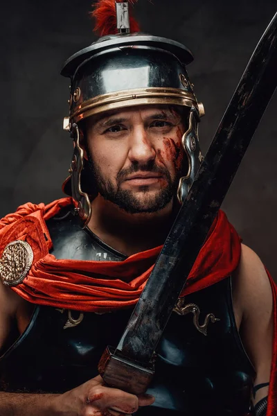 Warlike roman with dark armour and sword in dark background — Stock Photo, Image