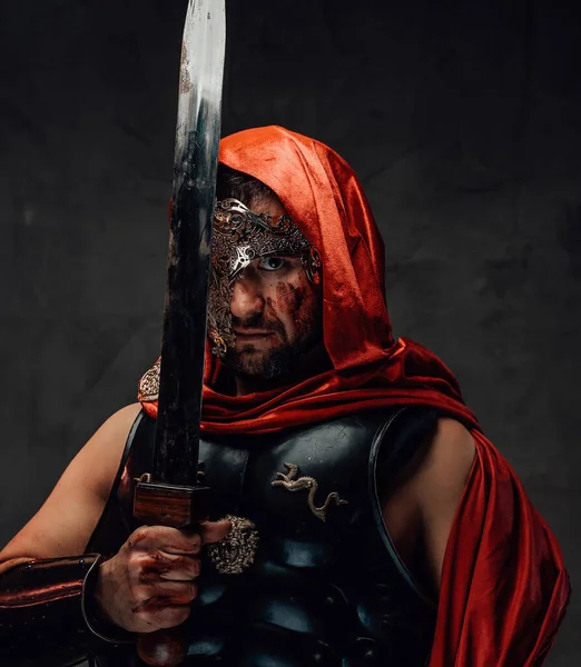 Asesino romano posando con espadas cerca de su cara en un fondo oscuro — Foto de Stock