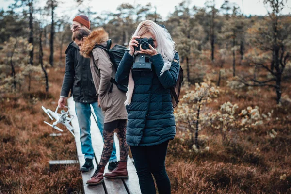 Schöne Mädchen Aufnahmen mit ihrer Kamera hinter ihren Freunden — Stockfoto