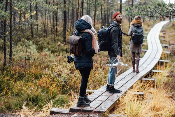 Group of three students going through wooden road in forest — Stock Photo, Image