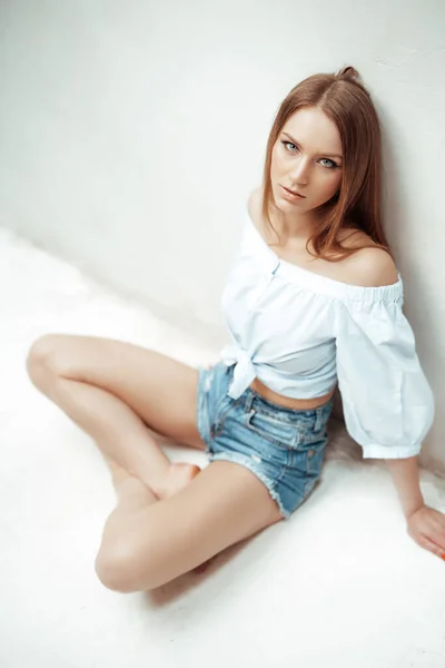 Weibliches Model mit braunen Haaren starrt in Wandnähe in die Kamera — Stockfoto